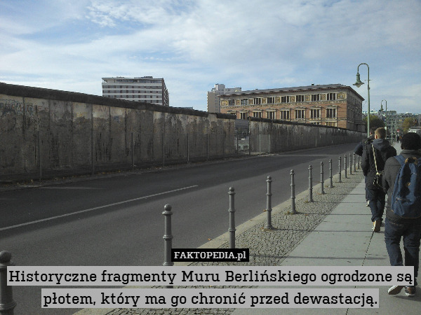 Historyczne fragmenty Muru Berlińskiego ogrodzone są płotem, który ma go chronić przed dewastacją. 