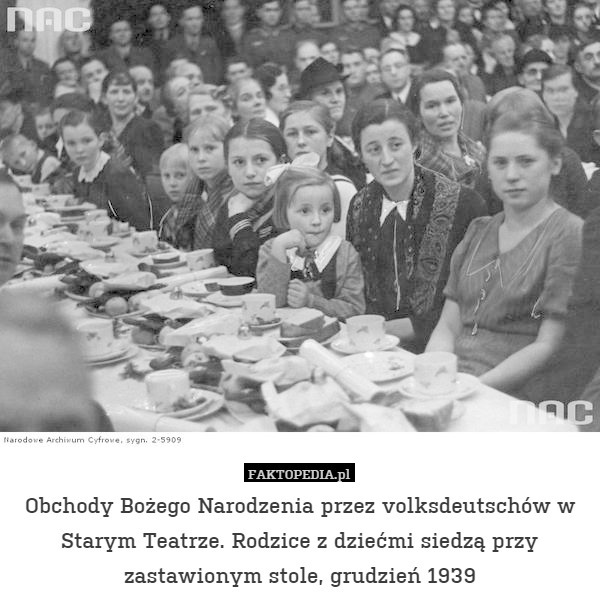 Obchody Bożego Narodzenia przez volksdeutschów w Starym Teatrze. Rodzice z dziećmi siedzą przy zastawionym stole, grudzień 1939 