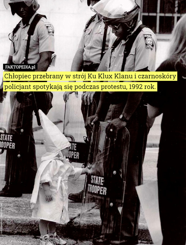 Chłopiec przebrany w strój Ku Klux Klanu i czarnoskóry policjant spotykają się podczas protestu, 1992 rok. 