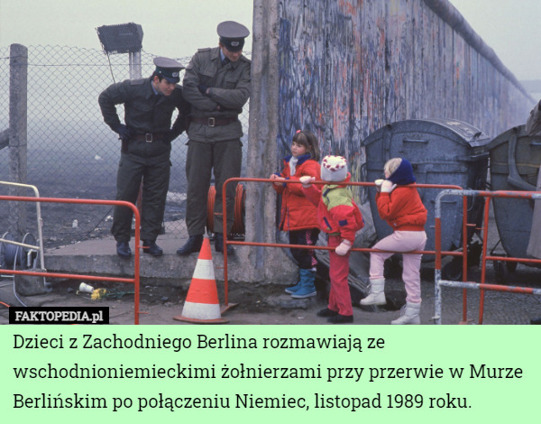 Dzieci z Zachodniego Berlina rozmawiają ze wschodnioniemieckimi żołnierzami przy przerwie w Murze Berlińskim po połączeniu Niemiec, listopad 1989 roku. 